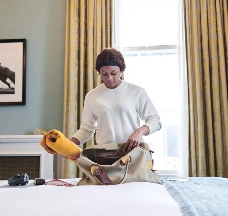 woman packing her baggage in hotel room