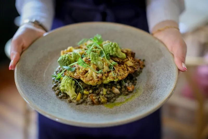 The Francis Hotel Bath waitress holding sustainable slow roasted cauliflower steak