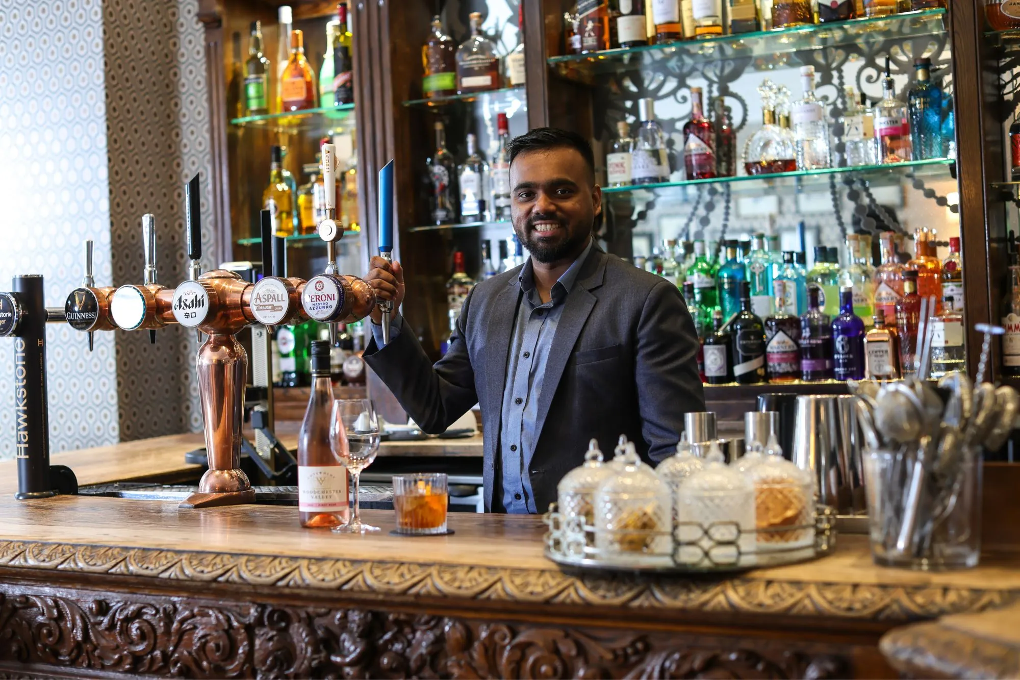 The Queens Hotel Cheltenham bar man smiling at the bar